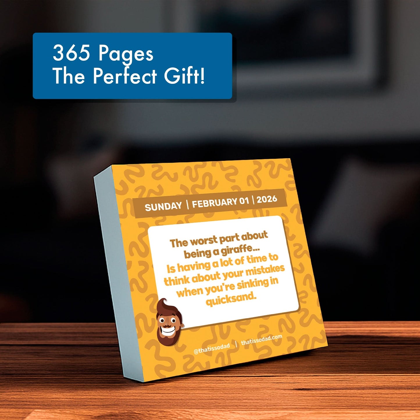 A PRE-ORDER 2026 Daily Dad Joke Desktop Calendar by That Is So Dad, featuring a funny giraffe and quicksand joke for February 1, is displayed on a wooden table—perfect for fans of daily joke calendars.