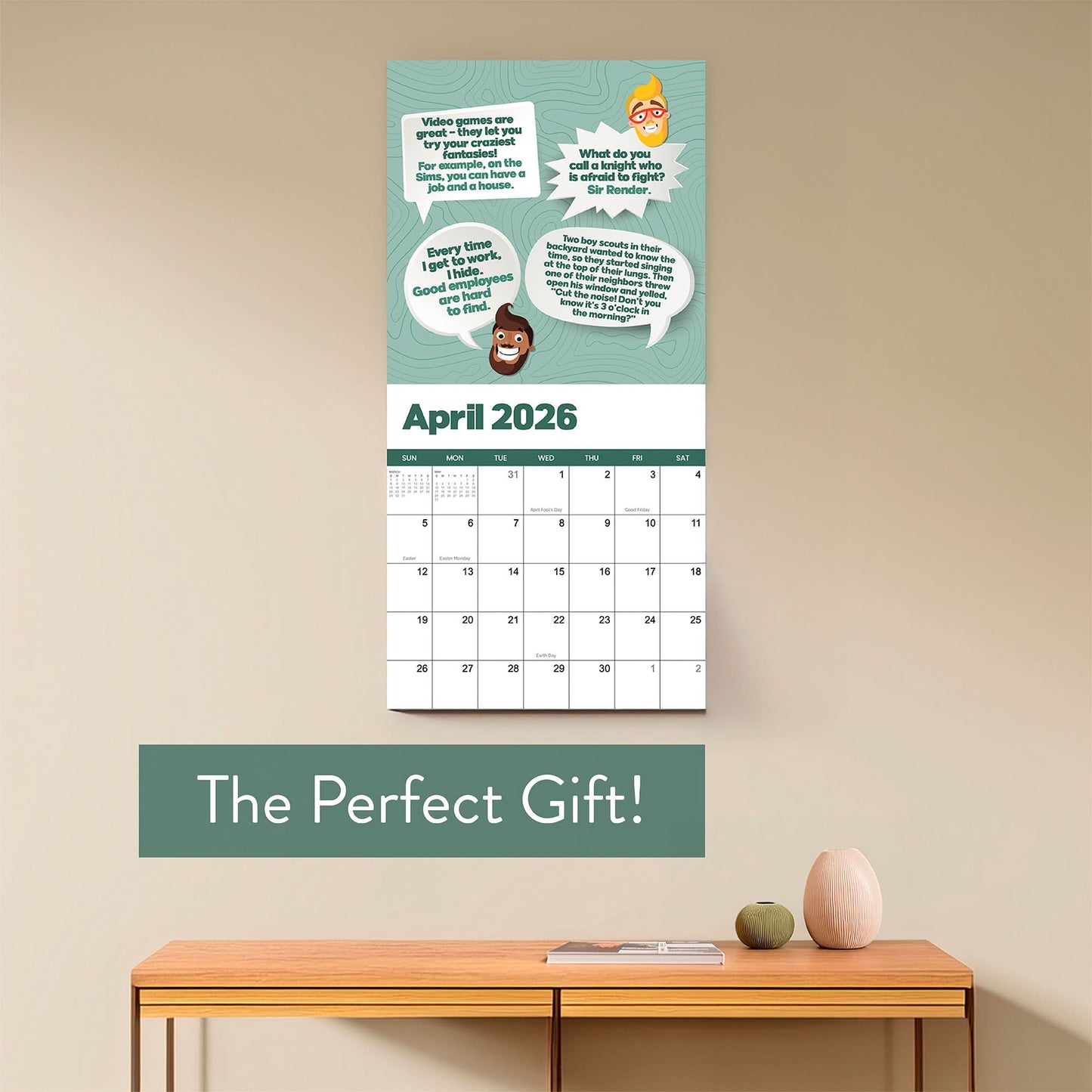 The 2026 Dad Joke Wall Calendar by That Is So Dad, with cartoon faces and witty quotes, hangs above a shelf with a vase, bowl, and small book. Text below says: “The Perfect Gift!”.