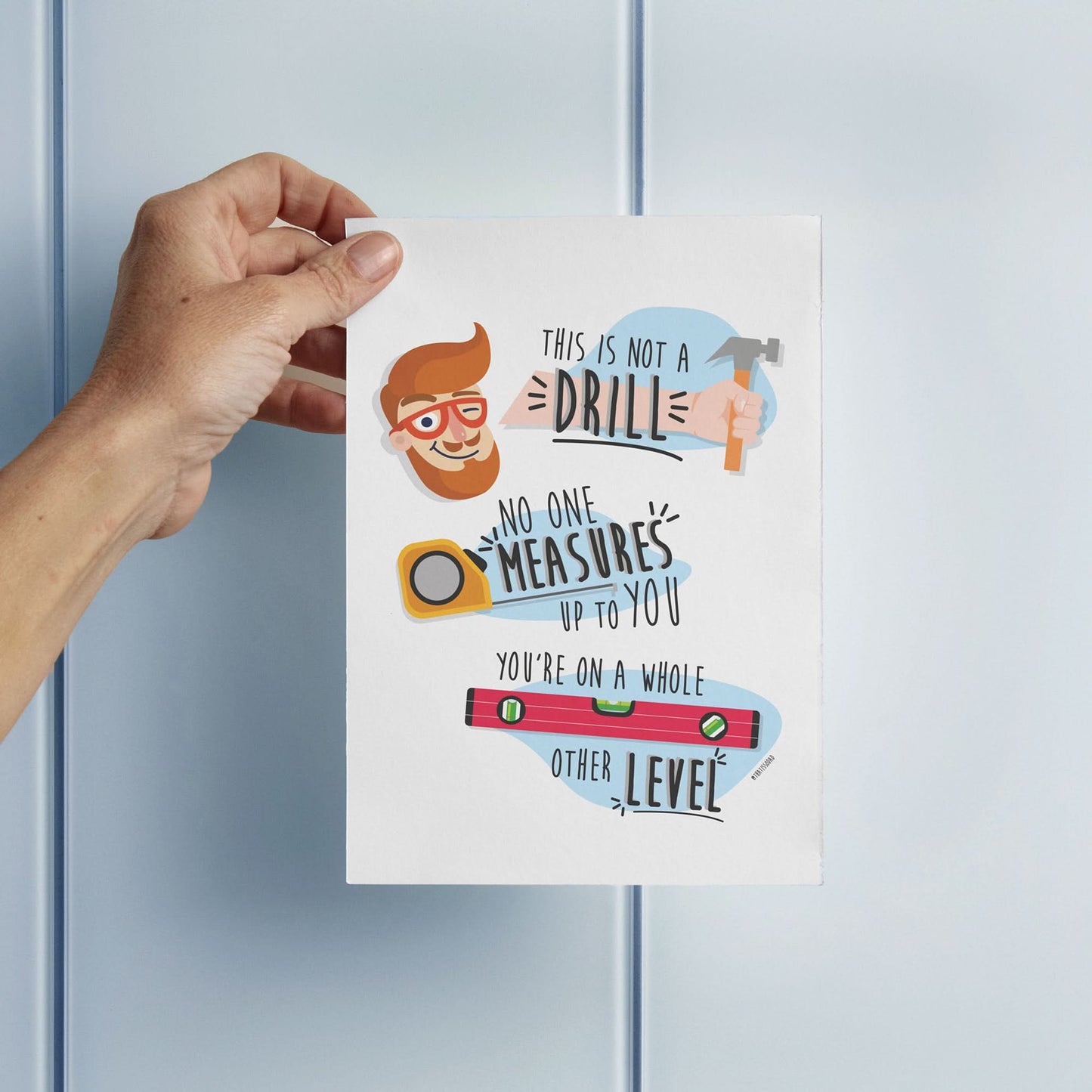 A hand holds the "This Is Not A Drill" funny Father's Day card by That Is So Dad, featuring cartoon tools and the message: "No one measures up to you. You're on a whole other level." Ideal for Father’s Day appreciation.