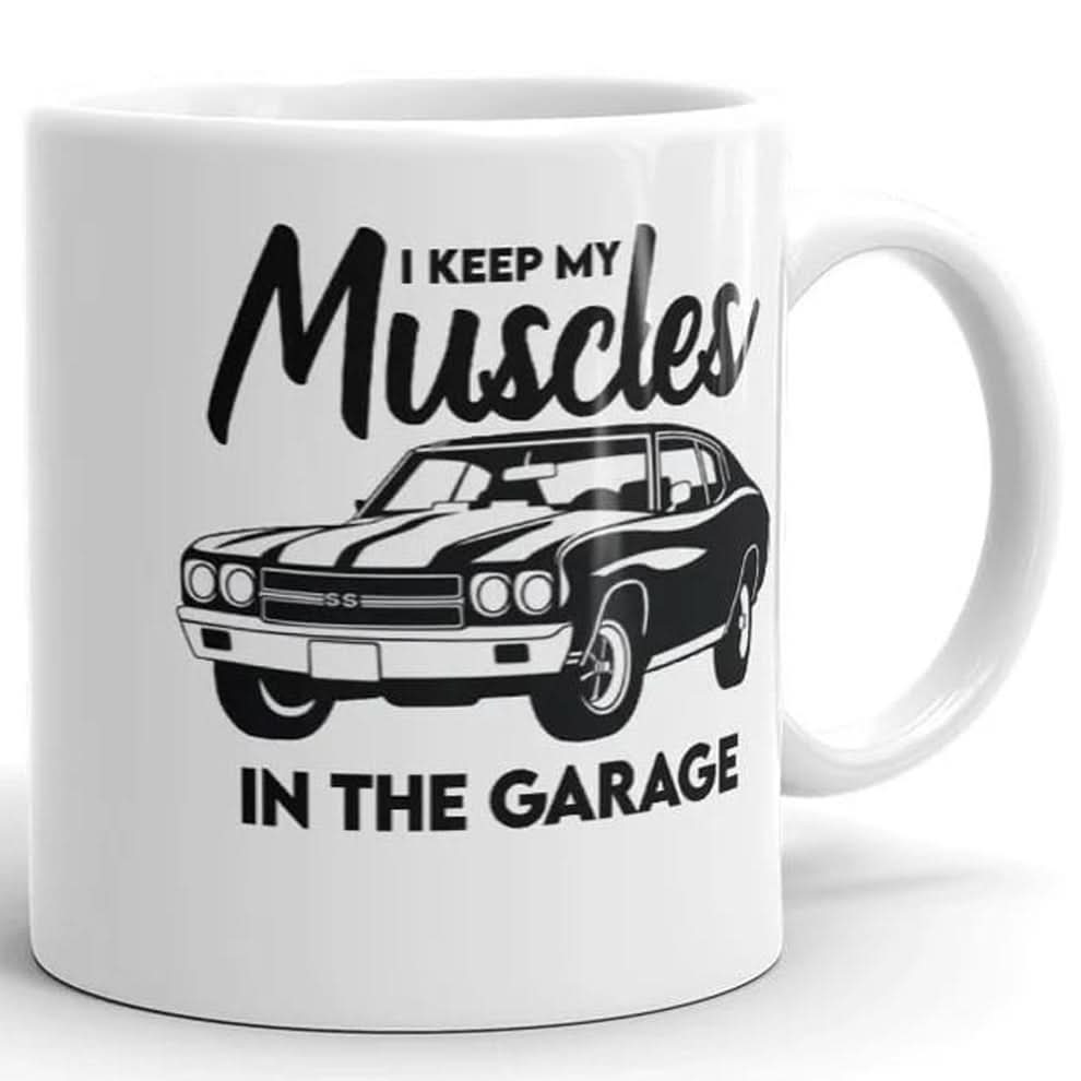 The Muscle In The Garage Mug by That Is So Dad is a white ceramic mug featuring a classic muscle car illustration and the phrase "I keep my muscles in the garage." Microwave safe, it’s perfect for car enthusiasts.