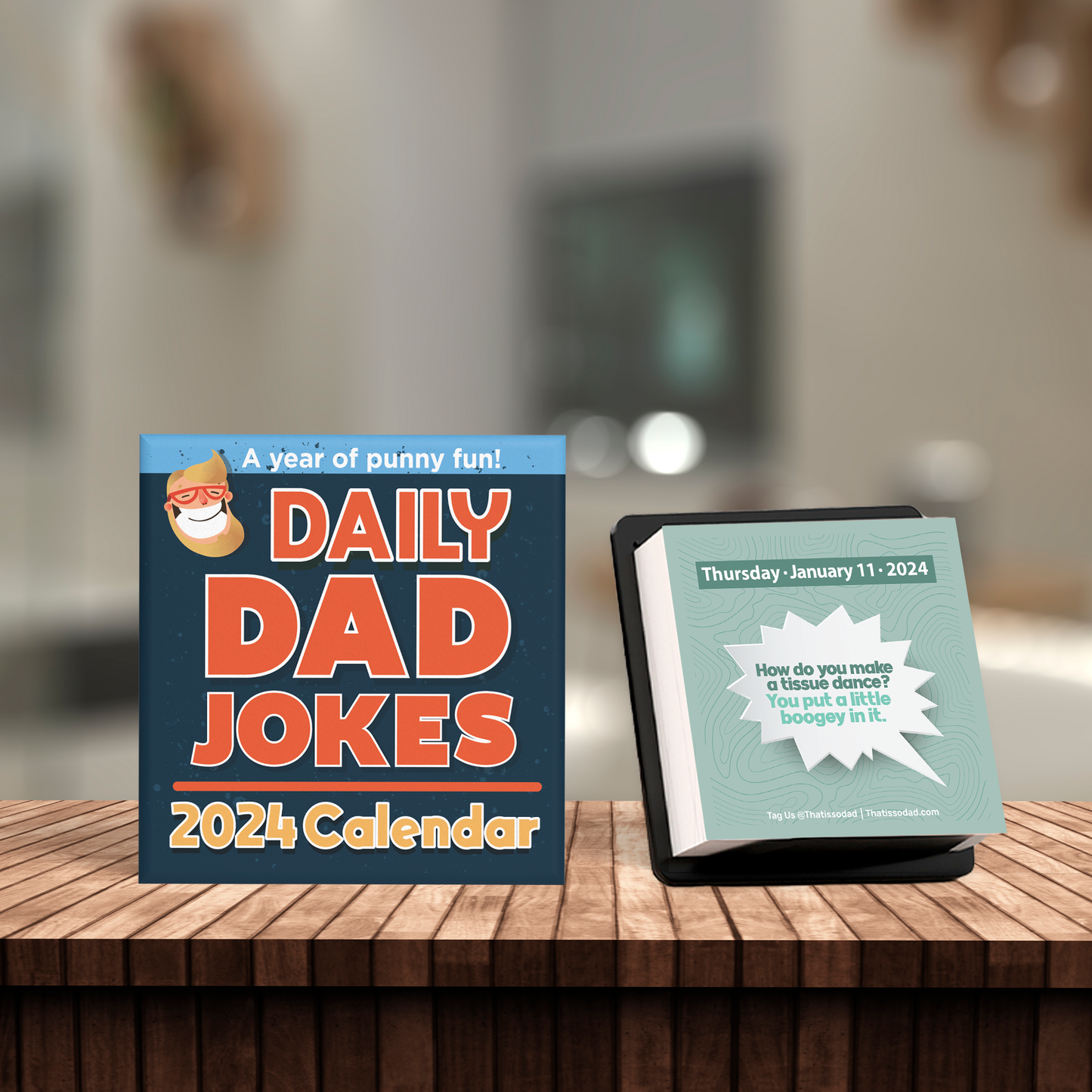 Two desktop calendars sit on a wooden table. The left one is from "That Is So Dad" and titled "2024 Dad Joke Calendar - Day to Day Jokes!" with a Santa illustration. The right one, part of the day-to-day calendar collection, displays a joke for Thursday, January 11, 2024, asking about tissue dance.