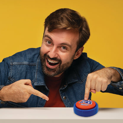 A bearded man in a denim jacket enthusiastically points at the "Dad Joke Button," a blue and red button from That Is So Dad, featuring 100+ corny jokes. The scene is set against a vibrant yellow background on a white surface.