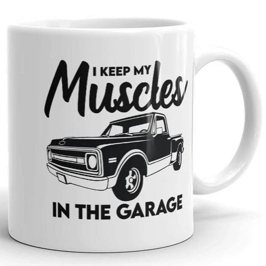 The Muscles In The Garage Mug by That Is So Dad is a white ceramic mug with a black vintage pickup truck illustration and the phrase "I keep my muscles in the garage." It's also dishwasher safe for easy cleaning.