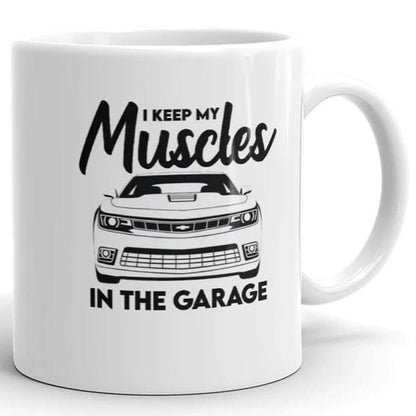The Muscles In The Garage Mug by That Is So Dad features a car graphic with "I keep my muscles in the garage" in bold black letters. This ceramic mug is dishwasher safe for easy cleaning.