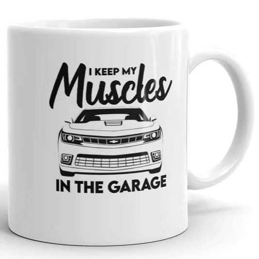 The Muscles In The Garage Mug by That Is So Dad features a car graphic with "I keep my muscles in the garage" in bold black letters. This ceramic mug is dishwasher safe for easy cleaning.